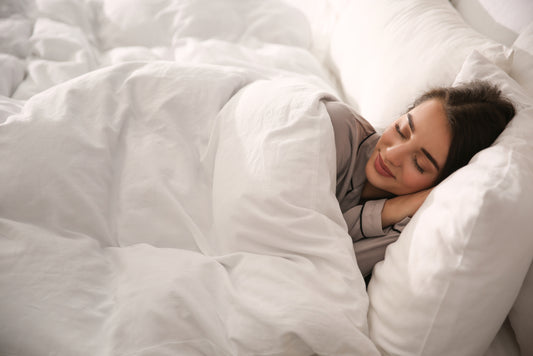 Beautiful young woman wrapped with soft duvet sleeping in bed at home